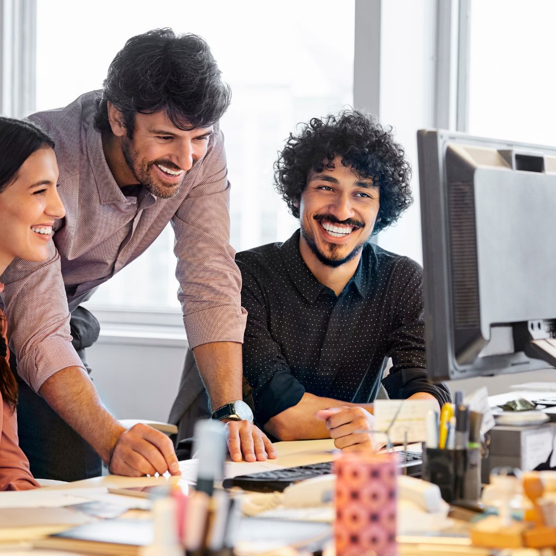 smiling office workers in front of desktop computer